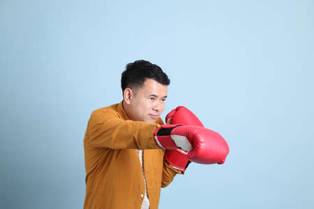 The Asian LGBTQ man with yellow shirt standing on the blue background.の写真素材