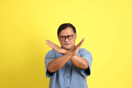 The adult Asian man with blue shirt standing on the yellow background.の写真素材