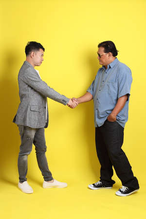 The adult two people standing on the yellow background.