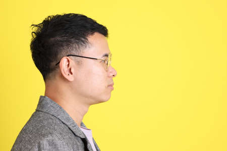 The Asian LGBTQ man with grey blazer standing on the yellow background.の写真素材