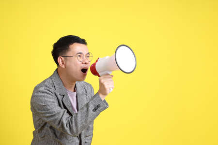 The Asian LGBTQ man with grey blazer standing on the yellow background.の写真素材
