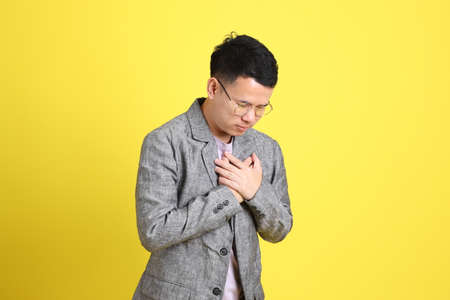 The Asian LGBTQ man with grey blazer standing on the yellow background.の写真素材