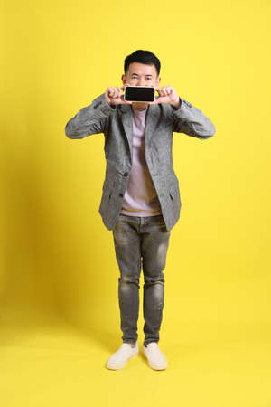 The Asian LGBTQ man with grey blazer standing on the yellow background.の写真素材