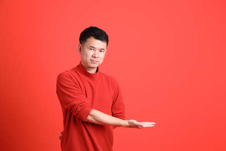 The Asian LGBTQ man with red shirt standing on the orange background.の写真素材