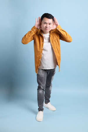 The Asian LGBTQ man with yellow shirt standing on the blue background.の写真素材