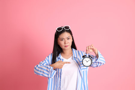 The Asian adult woman with casual clothes standing on the pink background.