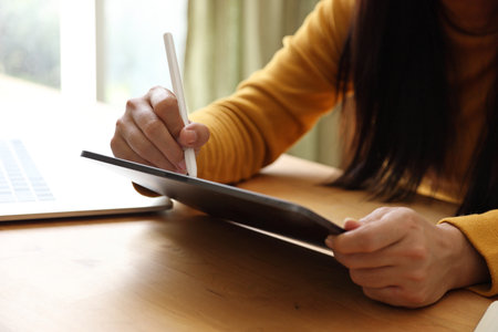 The Asian adult woman working on laptop in her home studio.