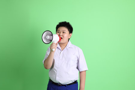 The Asian boy with student uniform on the green background.の写真素材