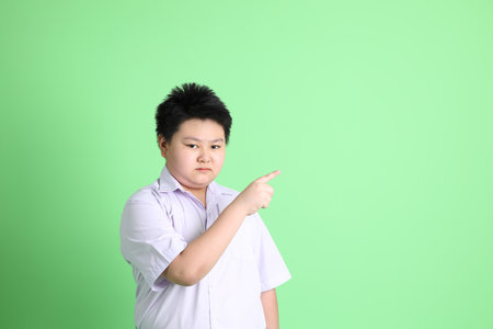 The Asian boy with student uniform on the green background.の写真素材