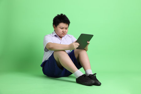 The Asian boy with student uniform on the green background.の写真素材