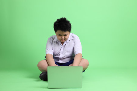The Asian boy with student uniform on the green background.