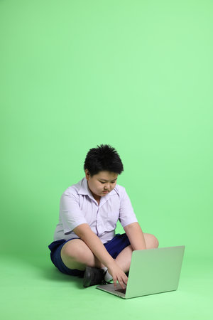 The Asian boy with student uniform on the green background.の写真素材
