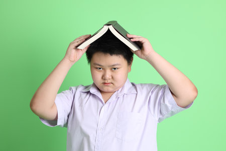 The Asian boy with student uniform on the green background.の写真素材