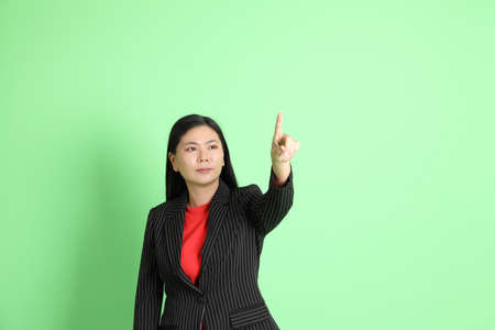 The Asian businesswoman standing on the pastel green background.の写真素材