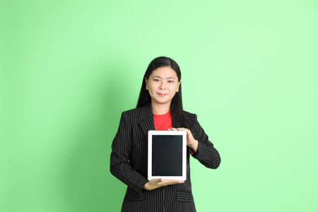 The Asian businesswoman standing on the pastel green background.