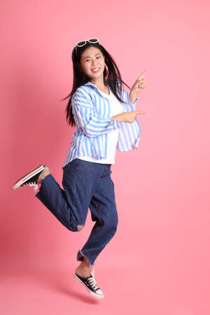 The Asian adult woman with casual clothes standing on the pink background.の写真素材