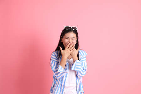 The Asian adult woman with casual clothes standing on the pink background.