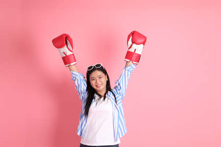 The Asian adult woman with casual clothes standing on the pink background.の写真素材