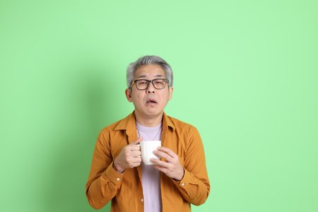 The 40s adult Asian man with yellow shirt standing on the green background.の写真素材