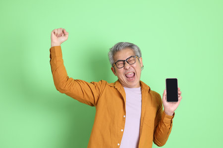 The 40s adult Asian man with yellow shirt standing on the green background.の写真素材