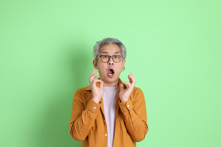 The 40s adult Asian man with yellow shirt standing on the green background.の写真素材