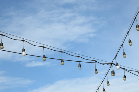 The light bulb hanging on the electric wire against the blue sky.の写真素材