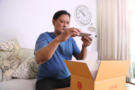The 40s adult Asian man taking the photos of the product in the mailbox.