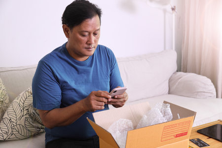 The 40s adult Asian man taking the photos of the product in the mailbox.の写真素材