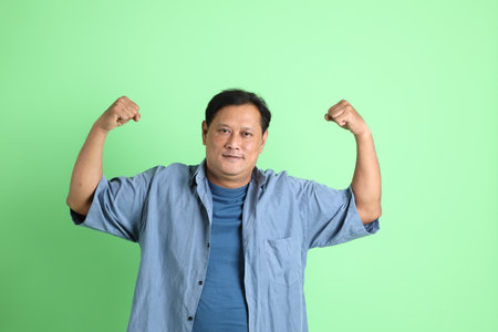The 40s adult overweight Asian man standing on the green background.の写真素材