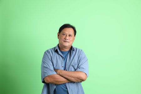 The 40s adult overweight Asian man standing on the green background.の写真素材