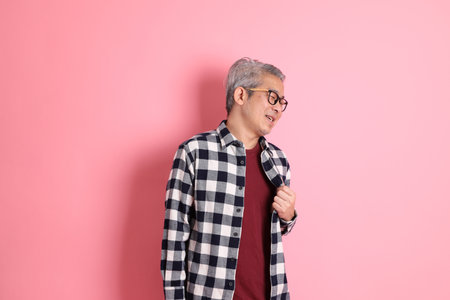 The 40s adult Asian man stnading on the pink background with casual clothes.の写真素材