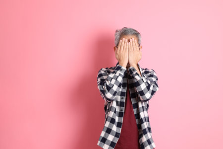The 40s adult Asian man stnading on the pink background with casual clothes.の写真素材