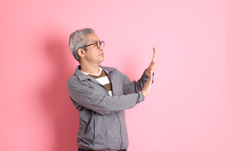 The 40s adult Asian man stnading on the pink background with casual clothes.の写真素材
