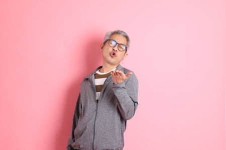 The 40s adult Asian man stnading on the pink background with casual clothes.の写真素材