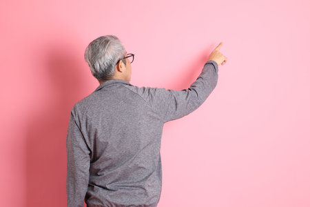The 40s adult Asian man stnading on the pink background with casual clothes.の写真素材