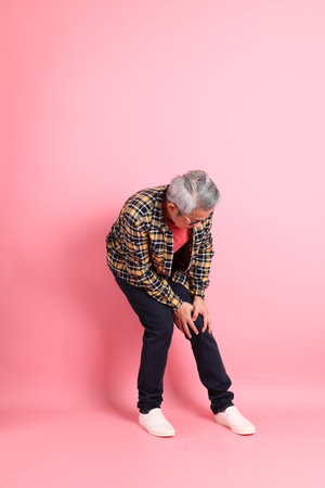 The full length of senior Asian man standing on the pink background.の写真素材