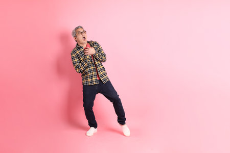 The full length of senior Asian man standing on the pink background.の写真素材