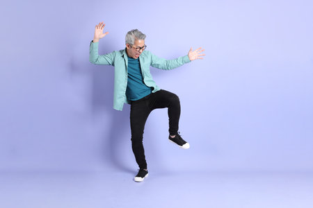 The full length of senior Asian man standing on the purple background.の写真素材