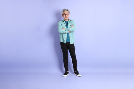 The full length of senior Asian man standing on the purple background.の写真素材