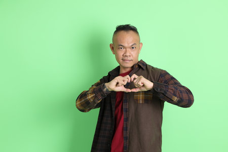 The 40s adult Asian man with plaid shirt standing on the green background.の写真素材
