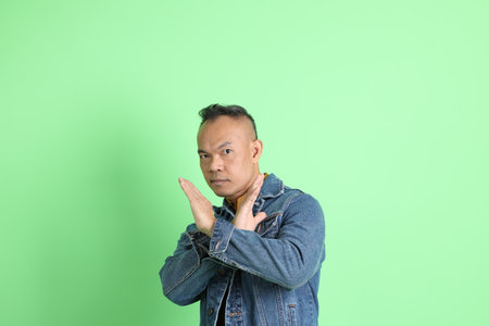 The 40s adult Asian man with jean shirt standing on the green background.の写真素材