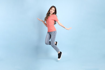The young adult Asian woman with casual clothes with jeans standing on the blue background.の写真素材