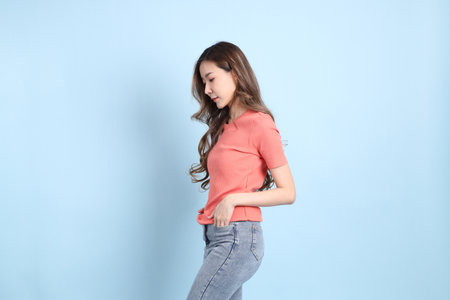 The young adult Asian woman with casual clothes with jeans standing on the blue background.