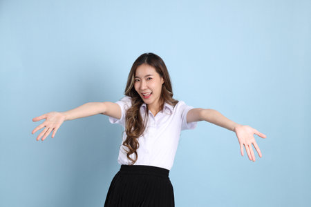 The young Asian student with uniform standing on the blue background.の写真素材
