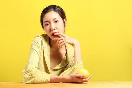 The beautiful  Asian woman showing skin with yellow background.の写真素材