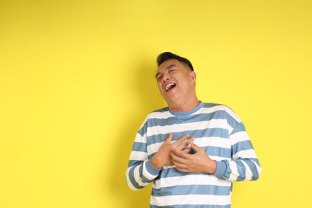 The 40s adult Asian man with standing on the yellow background.