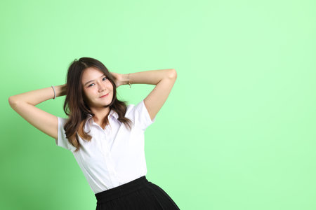 The young school girl with uniform standing on the green background.の写真素材