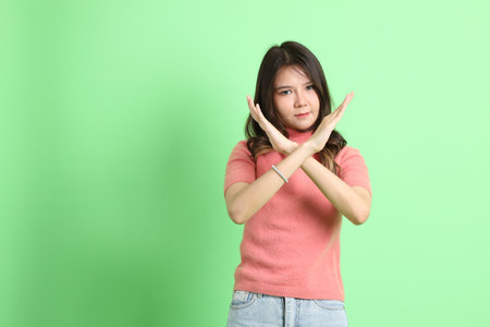 The young adult Asian woman with casual clothes with jeans standing on the green background.の写真素材