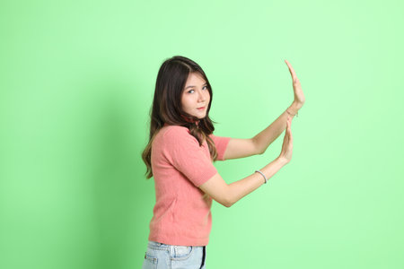 The young adult Asian woman with casual clothes with jeans standing on the green background.の写真素材