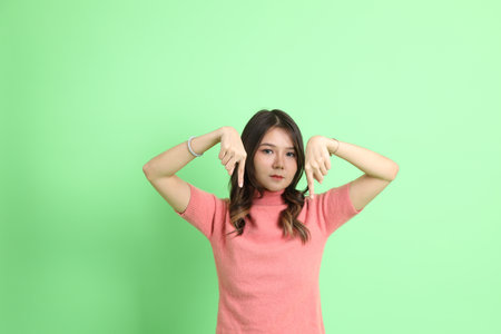 The young adult Asian woman with casual clothes with jeans standing on the green background.の写真素材